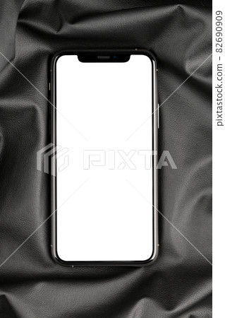 Smartphone with a blank white screen. New popular smartphone on black leather fabric. 82690909