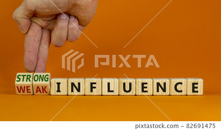 Weak or strong influence symbol. Businessman turns cubes and changes words 'weak influence' to 'strong influence'. Beautiful orange background. Business, weak or strong influence concept. Copy space. 82691475