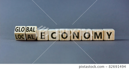Local or global economy symbol. Turned wooden cubes and changed words 'local economy' to 'global economy'. Beautiful grey background. Business and local or global economy concept. Copy space. 82691494