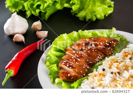 Homemade food - teriyaki chicken with white rice and pepper on a black background. Homemade food - teriyaki chicken with white rice and pepper on a black background. 82694327