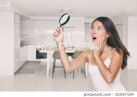 Home inspection funny contractor or inspector woman looking searching with magnifying glass for hidden vice, water damage, mold, cracks in ceiling, issues in kitchen 82697164