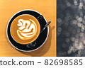 Latte art in a beautiful glossy black coffee cup on a wooden table 82698585