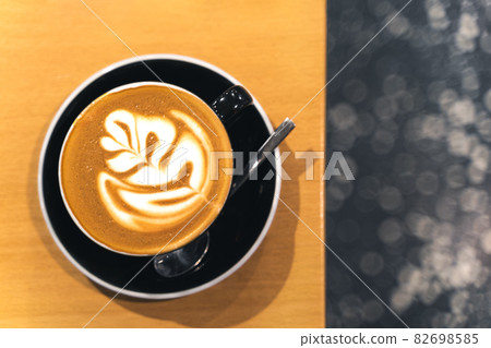 Latte art in a beautiful glossy black coffee cup on a wooden table Latte art in a beautiful glossy black coffee cup on a wooden table 82698585