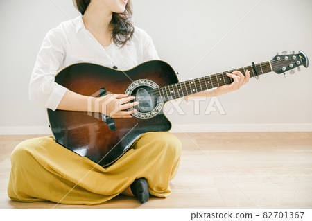 Woman playing the guitar Woman playing the guitar People playing the guitar in the room 82701367