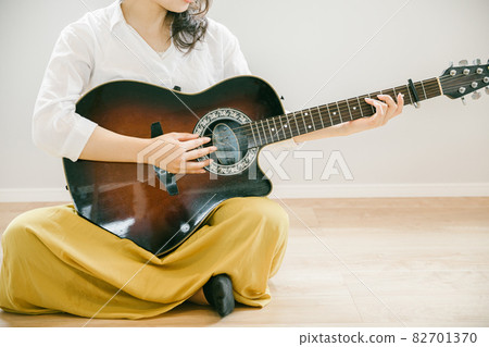 Woman playing the guitar Woman playing the guitar People playing the guitar in the room 82701370