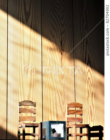 Light and shadow illuminating two mini chairs and one table 82704902