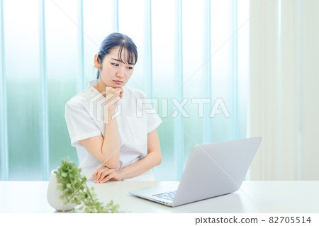 A woman in a white coat using a computer (problem) A woman in a white coat using a computer (problem) 82705514