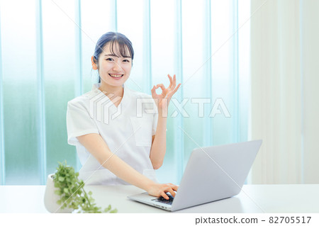 A woman in a white coat using a computer 82705517