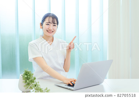 A woman in a white coat using a computer 82705518