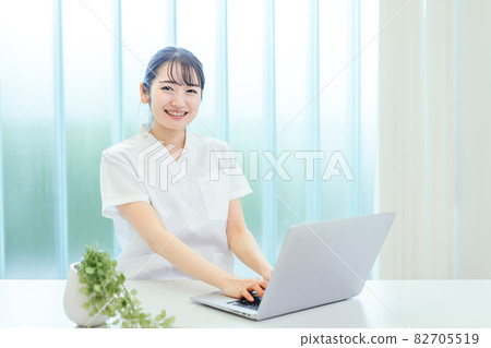 A woman in a white coat using a computer 82705519