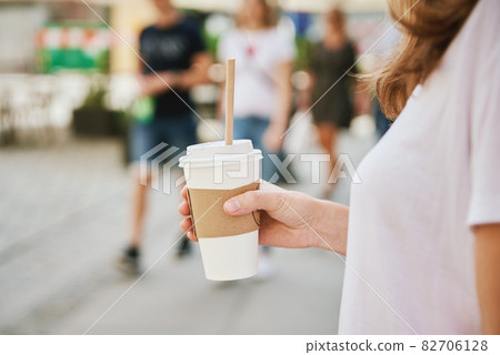Woman walks at city street with paper coffee cup. Woman walks at city street with paper coffee cup. 82706128