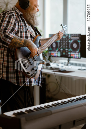 Inspired man plays electric guitar recording music with modern equipment at home Inspired man plays electric guitar recording music with modern equipment at home 82706985