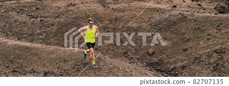 Man trail running in the mountain hills nature landscape. Ultra runner competing on cross country race working out endurance on volcanic rocks outdoor path. Header landscape banner 82707135