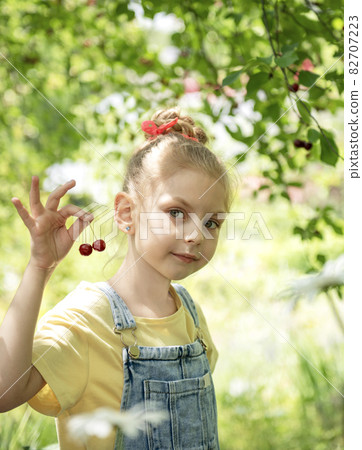 Little girl is picking cherries in the garden. Little girl is picking cherries in the garden. 82707223