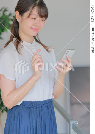 A woman looking at a smartphone and smiling 82708545