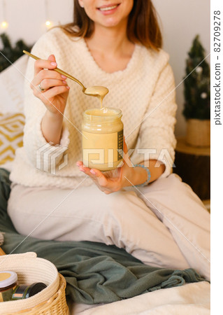 Happy Woman Eating Peanut Butter on a Spoon 82709278