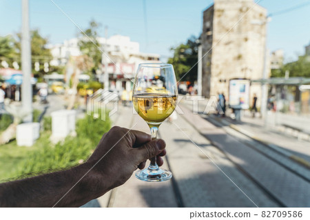 A glass of white wine against the background of the streets of Antalya in Turkey. Summer, travel, lifestyle, relaxation, and enjoyment concept. A glass of white wine against the background of the streets of Antalya in Turkey. Summer, travel, lifestyle, relaxation, and enjoyment concept. 82709586