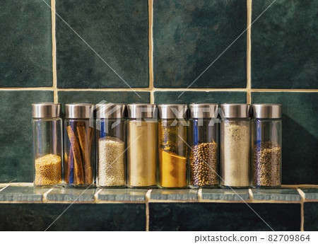 Spices in glass jars in the kitchen. A set of spices (turmeric, coriander, pepper, cinnamon, mustard) for home cooking 82709864