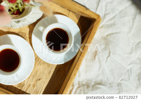 Breakfast in bed, try with two cups coffee and flower in sunlight at home Breakfast in bed, try with two cups coffee and flower in sunlight at home 82712027