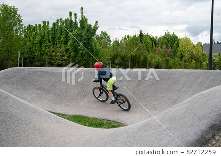 Young boy riding a pump track with bmx bike 82712259
