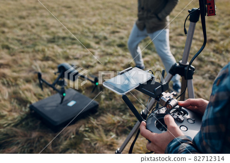 Man pilot controlling quadcopter drone with remote controller pad Man pilot controlling quadcopter drone with remote controller pad 82712314