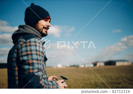 Man pilot controlling quadcopter drone with remote controller pad Man pilot controlling quadcopter drone with remote controller pad 82712319