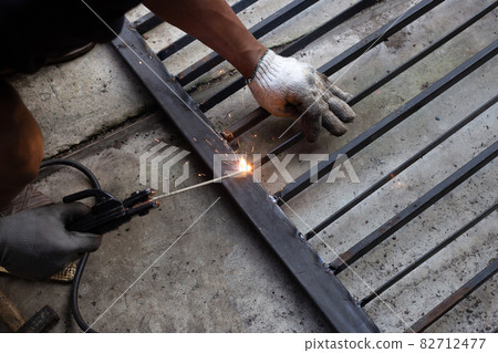 Iron gate repair, Worker hand welding steel 82712477
