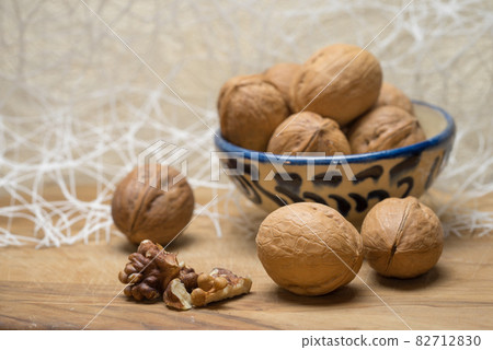 Walnut chopped nuts kernels and whole walnuts lie on a wooden table. Walnut chopped nuts kernels and whole walnuts lie on a wooden table. 82712830
