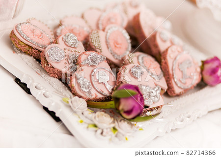 Delicious desserts at the wedding candy bar in the buffet area: cookies covered with icing, decorated with angels, cameo, sugar rosebuds and silver dye. 82714366