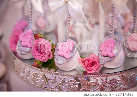 Delicious desserts at the wedding candy bar in the buffet area: cake pops decorated with angels and cameo and fresh rosebuds. Delicious desserts at the wedding candy bar in the buffet area: cake pops decorated with angels and cameo and fresh rosebuds. 82714382