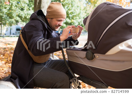 Father with baby In Park taking a photo by mobile phone Father with baby In Park taking a photo by mobile phone 82714599