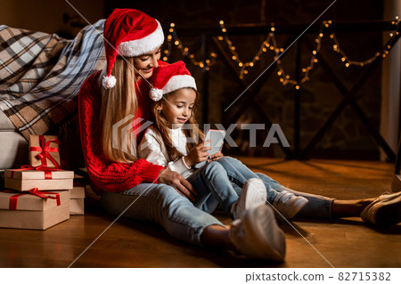 Portrait of happy festive woman and daughter using phone 82715382