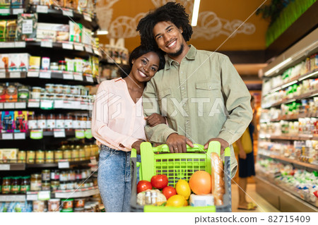 Black Couple On Grocery Shopping Posing With Shop Cart Indoor Black Couple On Grocery Shopping Posing With Shop Cart Indoor 82715409