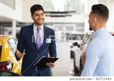 Cheerful car salon manager having conversation with male customer 82715495