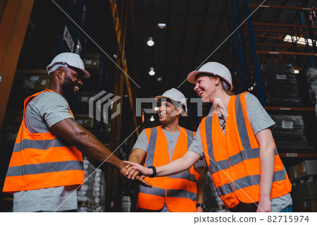 A Group of Diversity warehouse workers giving hand for high-five after success the project and celebrating together in a distribution center warehouse. 82715974
