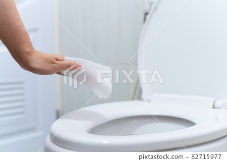close up hand cleaning Toilet seat by a wet wipe with alcohol spray in public restroom for coronavirus prevention and hygiene before using 82715977