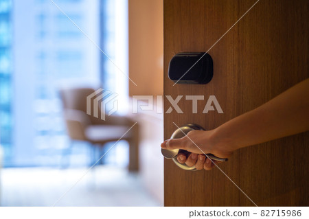 Female hand grabbing doorknob opening room for access, selective focused 82715986