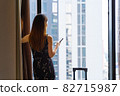 Portrait rear view of woman standing close to the window in hotel room after check-in 82715987