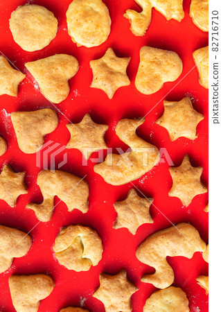 Flat lay top above view of sweet tasty delicious curd ginger cookies baked in hot oven stove on red bright silicone bakery mat at home kitchen. Homemade hot biscuits pattern background 82716710