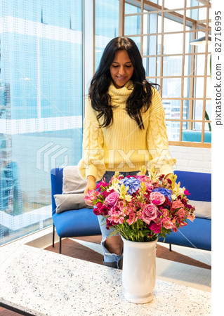 Empowered brunette woman is relaxed enjoying her flower arrangement 82716995