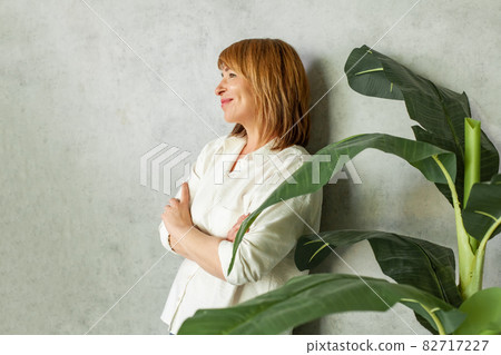 Smiling mature woman with red hair on gray background Smiling mature woman with red hair on gray background 82717227