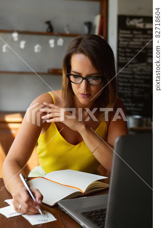 Portrait of businesswoman with pen in his hand with weekly and laptop works remotely in cafe Portrait of businesswoman with pen in his hand with weekly and laptop works remotely in cafe 82718604
