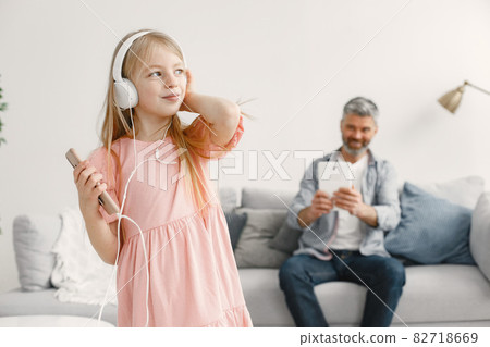 Little girl listening music in headphones with grandfather 82718669