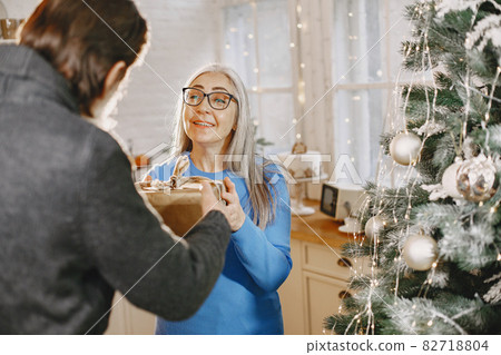 Senior couple with gifts near the Christmas tree Senior couple with gifts near the Christmas tree 82718804