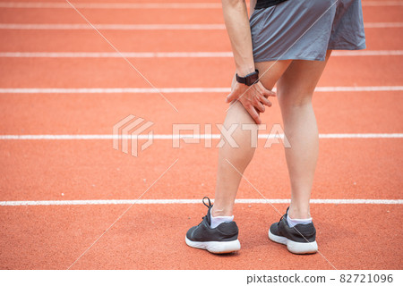 Close up of runner woman holding her leg, suffuring from ITB Syndrome caused by altered running biomechanics due to underlying muscular imbalances. 82721096