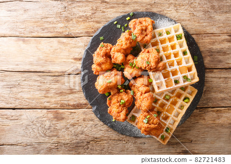 Crispy breaded chicken with tender Belgian waffles close-up on a slate plate. horizontal top view 82721483