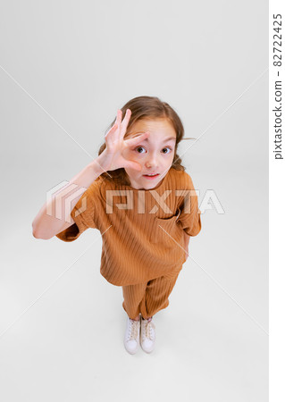 Portrait of little Caucasian girl, child making big eyes and posing isolated over gray background Portrait of little Caucasian girl, child making big eyes and posing isolated over gray background 82722425