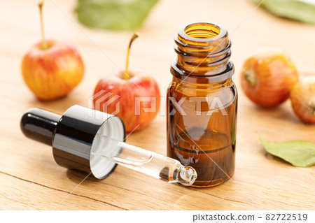 Apple essential oil bottle and pipette on wooden table. Apple oil 82722519