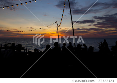 Lamp string hanging against sunset sky by the sea Lamp string hanging against sunset sky by the sea 82722523