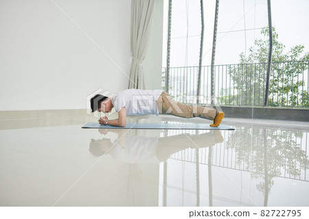 Young Asian man planking on an exercise mat at home Young Asian man planking on an exercise mat at home 82722795